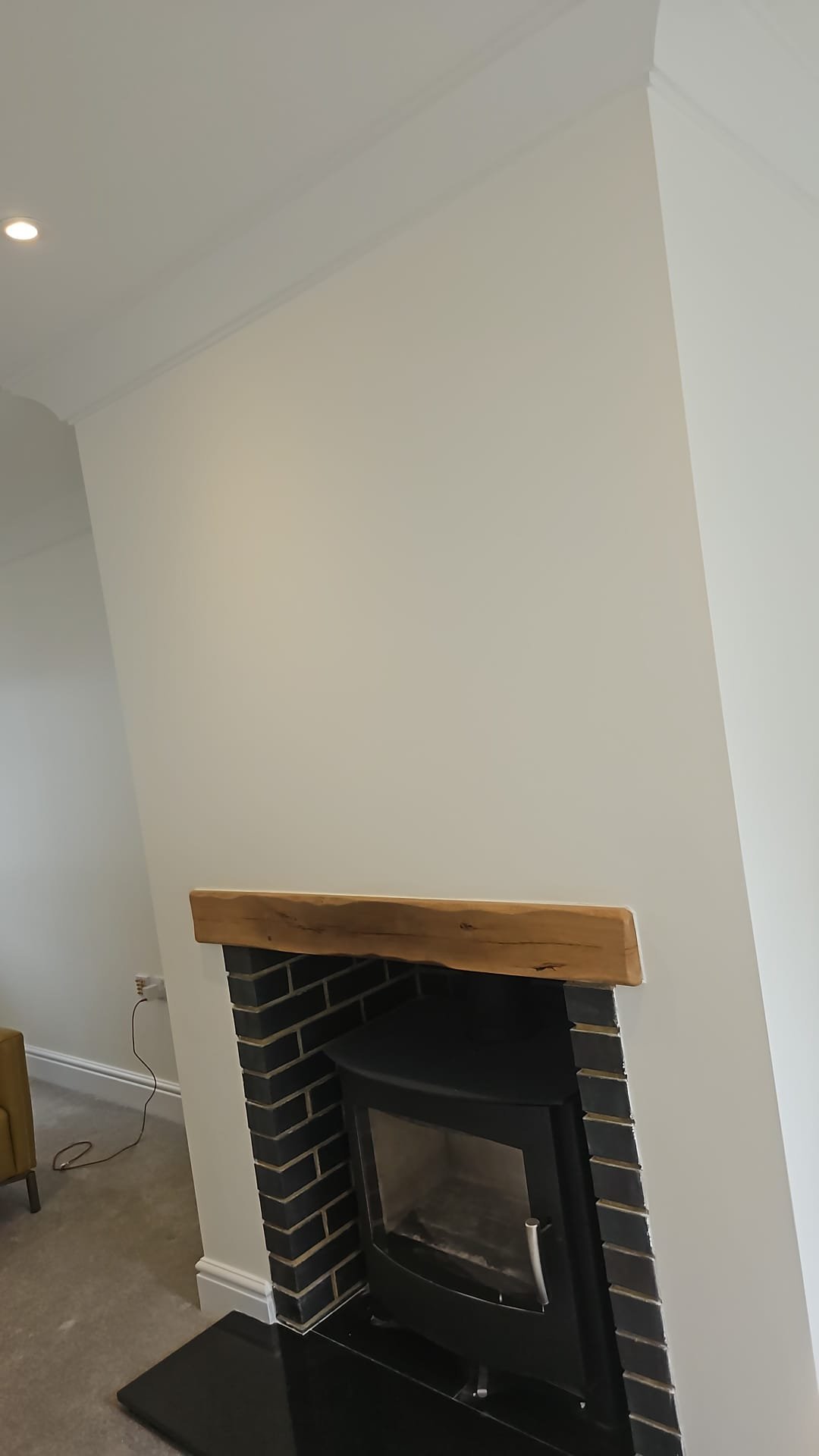 Modern fireplace with black brick surround, wooden mantel, and white walls in minimalist interior