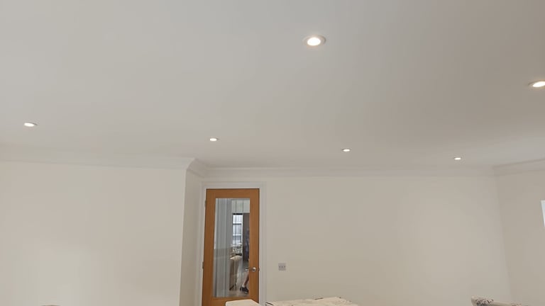 Interior room with wooden door frame, recessed ceiling lights, and plain white walls under construction
