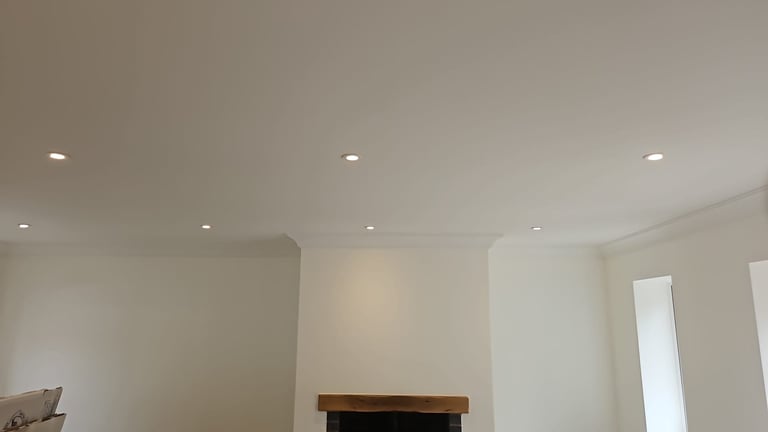 Modern interior ceiling with recessed lighting fixtures and white walls with partial furniture visible below