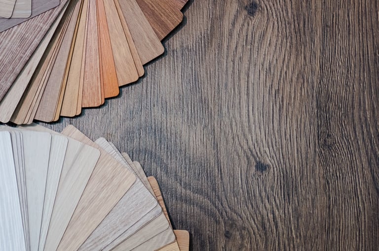 Wood flooring samples fanned out showing light and dark finish options alongside a dark wood floor surface
